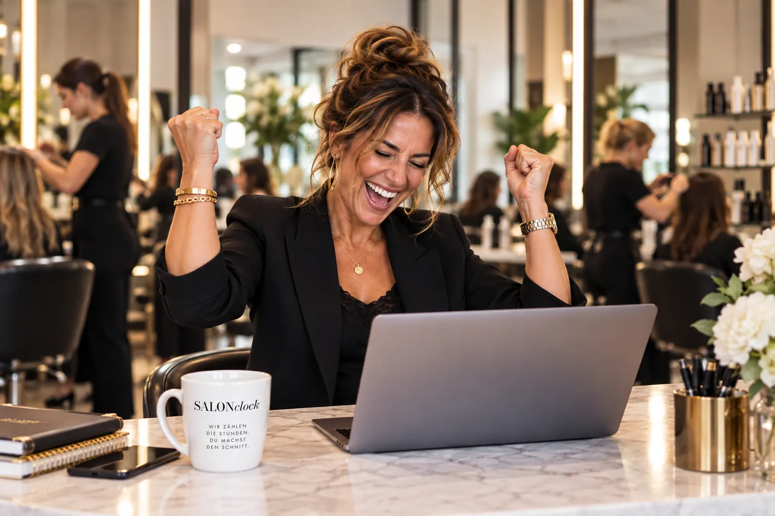 Salon-Inhaberin jubelt am Laptop, im Hintergrund arbeitet ihr Team